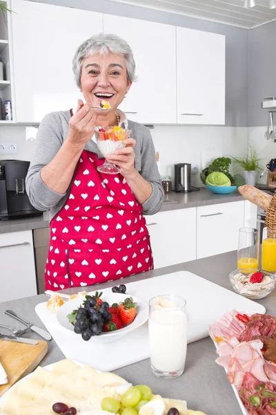 Seniorin oder ältere Frau mit grauen Haaren kocht in Küche. — Stockfoto