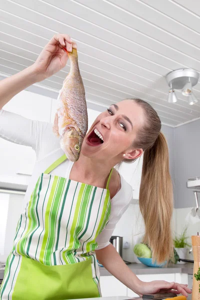 Vrouw is de draak met verse vis - baars of pike - in kitchen. Stockfoto