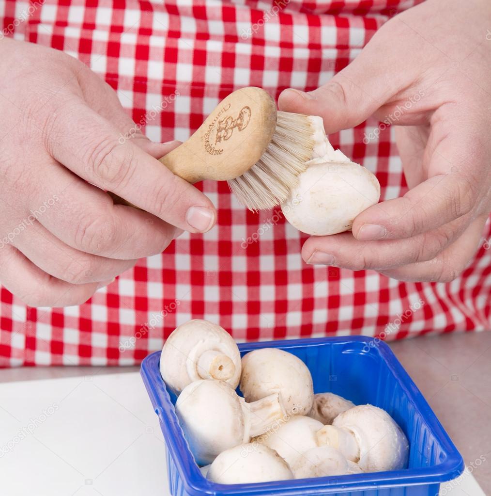 Woman cleaning mushrooms with vegetable brush.