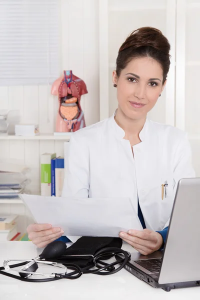 Portret van dokter achter haar computer op haar kantoor zit — Stockfoto