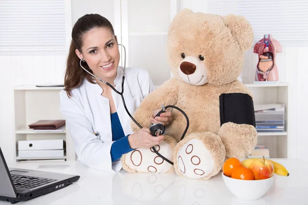 Νεαρό γιατρό για τα παιδιά με ένα αρκουδάκι. — Φωτογραφία Αρχείου