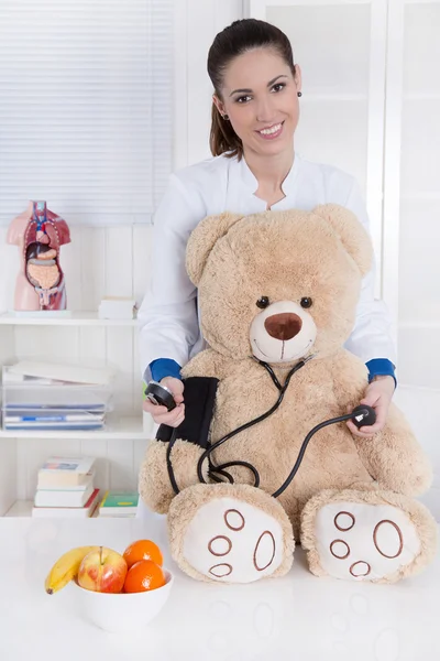 Profissão: Young female doctor with a teddy bear . — Fotografia de Stock