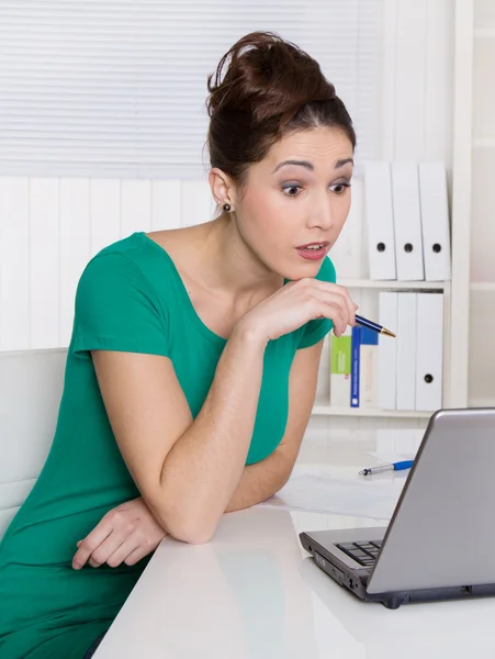 Giovane donna in verde fissando il computer portatile . — Foto Stock