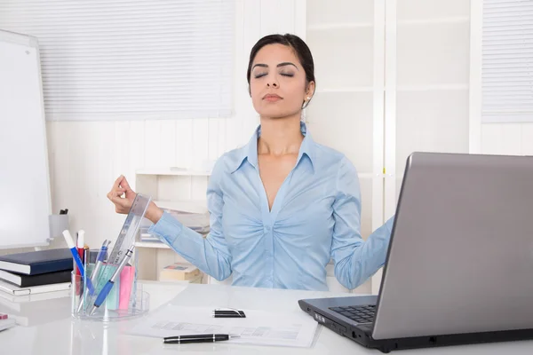Attractive secretary with closed eyes is doing meditation at off Stock Picture