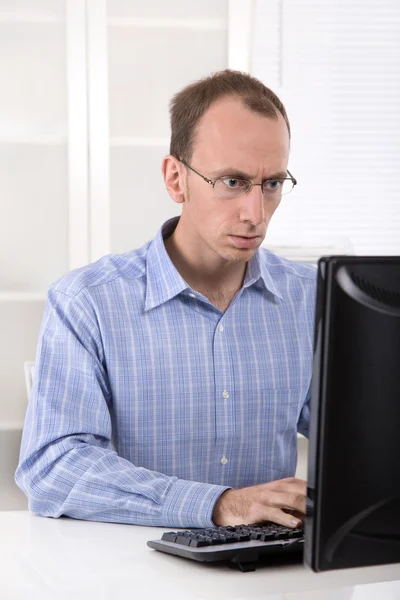 コンピューターはオフィスで働いて青いシャツを着てハゲ実業家. ストック画像