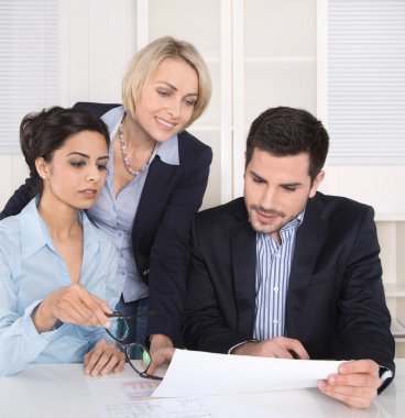 Teamwork between three business people at desk at office.