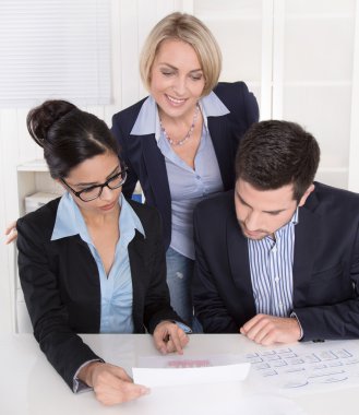 Teamwork between three business people at desk at office.