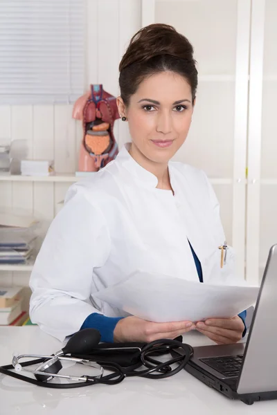 Ritratto di giovane medico attraente in uniforme alla scrivania . — Foto Stock