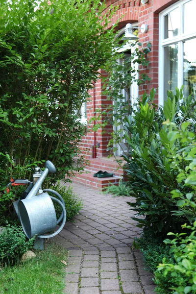 Fermer d'un chemin pavé avec façade de la maison et arrosoir . — Photo