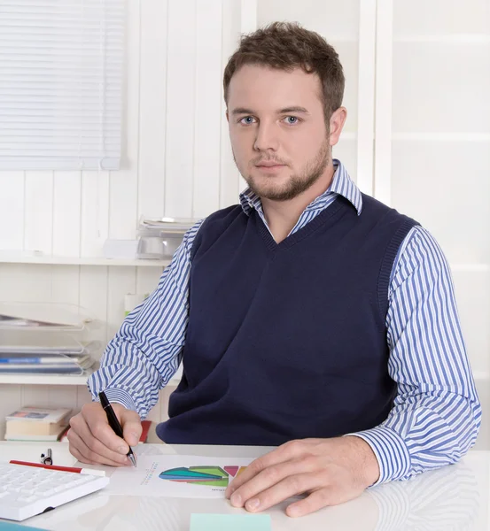 Young handsome bookkeeper working with graphs at desk. — Stock Photo, Image