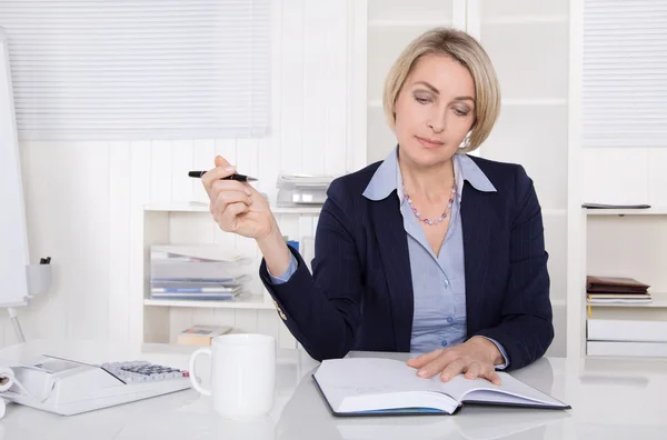 Seniorin plant am Schreibtisch. — Stockfoto