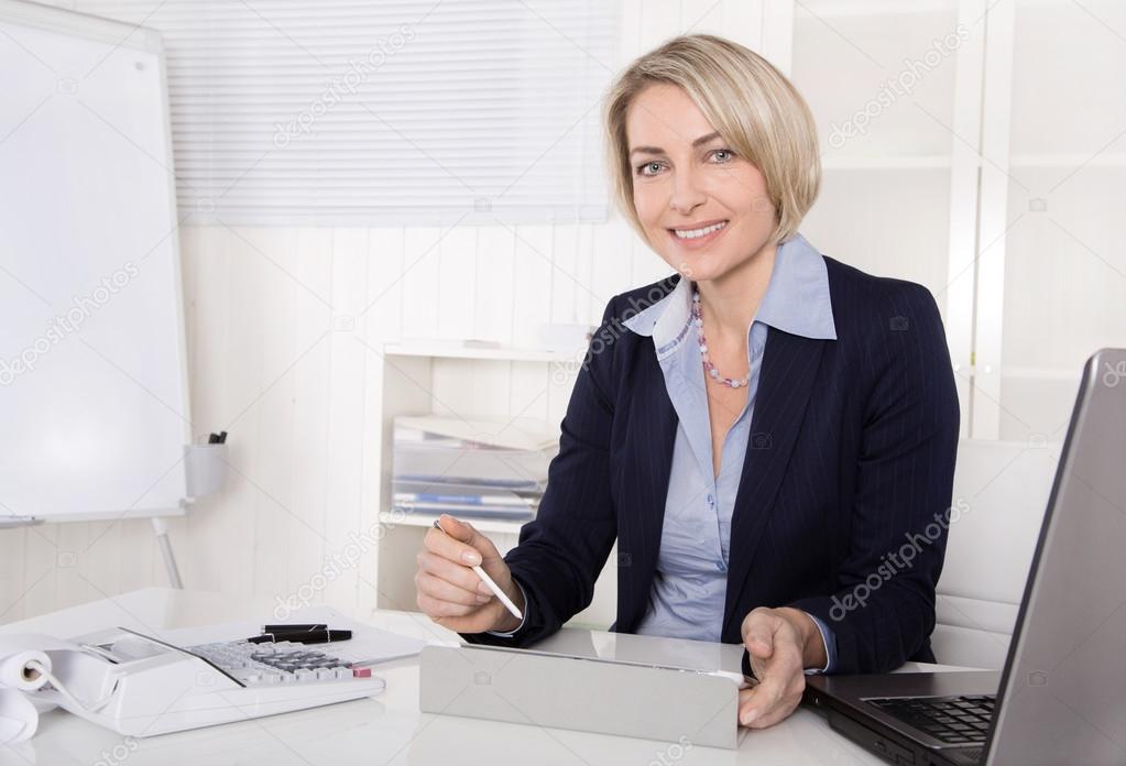 Attractive happy older or senior business woman in the office.