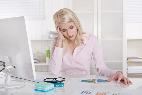 Young blonde trainee in rose blouse with headache at desk. — Stock Photo, Image