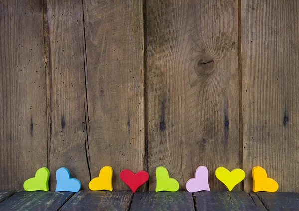 Bunte Herzen auf einem hölzernen Hintergrund für eine Grußkarte. — Stockfoto