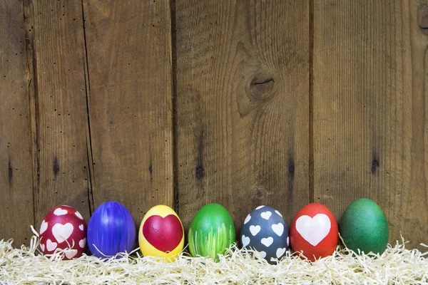 Tarjeta de felicitación de Pascua con coloridos huevos diferentes en madera . — Foto de Stock