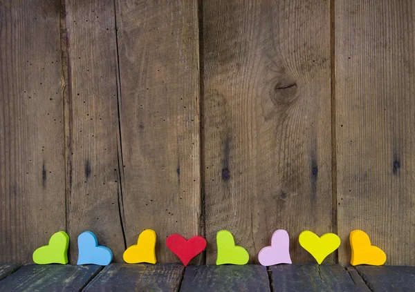 Kleurrijke harten op een houten achtergrond voor een wenskaart. Stockfoto