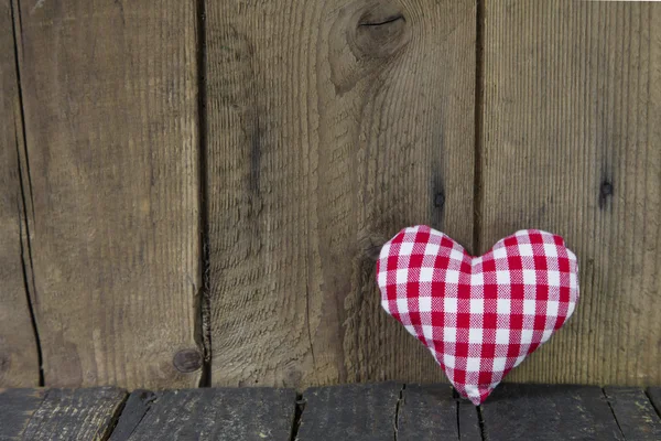 Red white checked sewed heart on a wooden background. — Stock Photo, Image