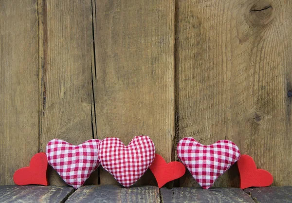 Country style: red white checkered hearts on wooden background. Stock Photo