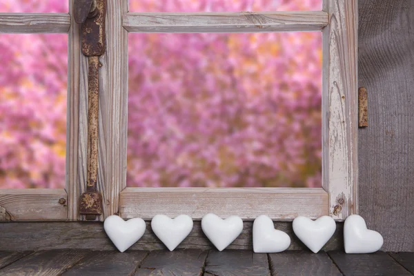 Drewniane okna z widokiem na ogród i białe serca — Zdjęcie stockowe