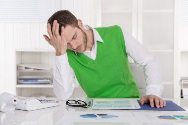 Unhappy businessman sitting concerned and frustrated at office. clipart