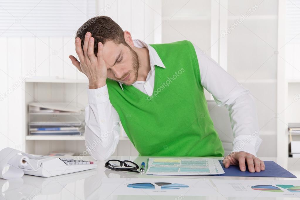 Unhappy businessman sitting concerned and frustrated at office.