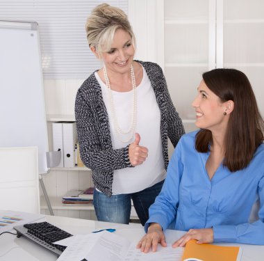 Female boss praise her young assistant in the office. clipart