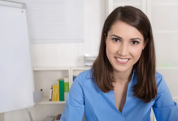 Успешная молодая улыбающаяся деловая женщина, сидящая в своем офисе . — стоковое фото