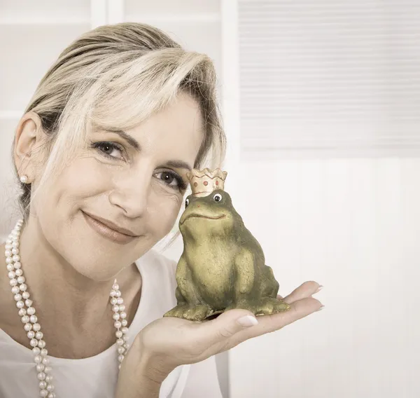 Enkele aantrekkelijke oudere vrouw met een kikker koning in haar handen. — Stockfoto