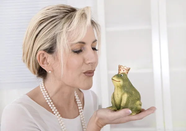 Single attractive older woman with a frog king in her hands. — Stock Photo, Image