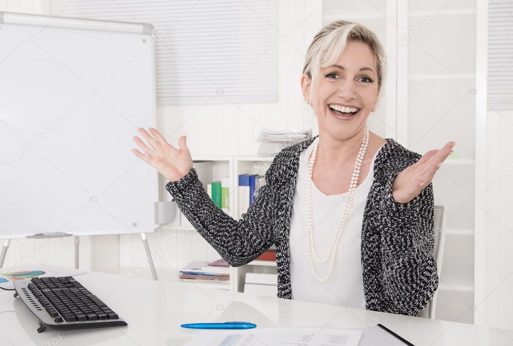 Satisfied and cheering business woman sitting at desk.