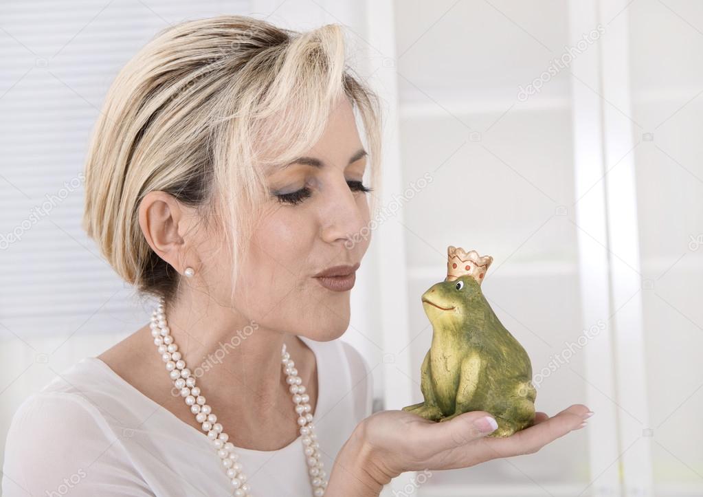 Single attractive older woman with a frog king in her hands.