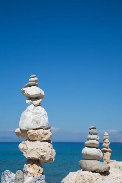 Pyramid of stones at the ocean. Blue water background. — Stock Photo, Image