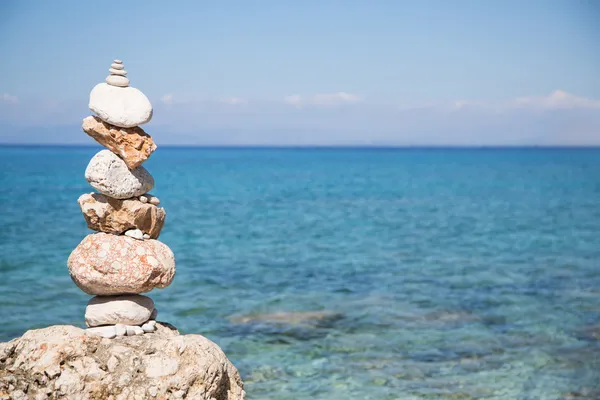 Pyramid of stones at the ocean. Blue water background. — Stock Photo, Image