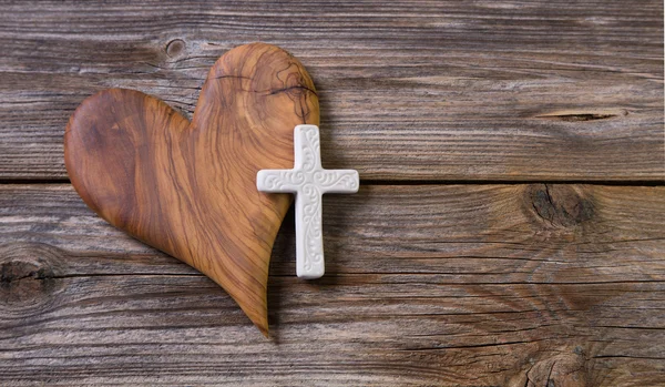 Деревянный фон с оливковым сердцем и белым крестом для некролога — стоковое фото