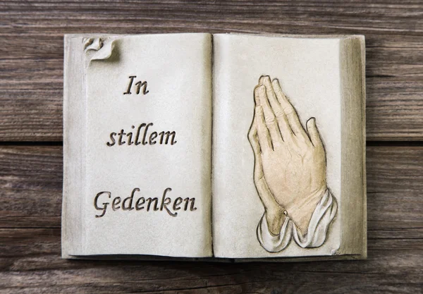 Rouw: bidden handen op een boek van steen — Stockfoto