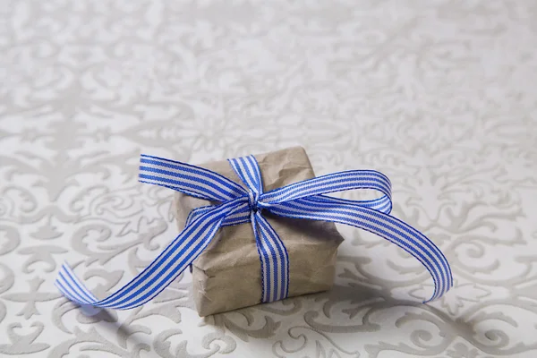 Present with blue striped ribbon isolated on grey background. — Stock Photo, Image