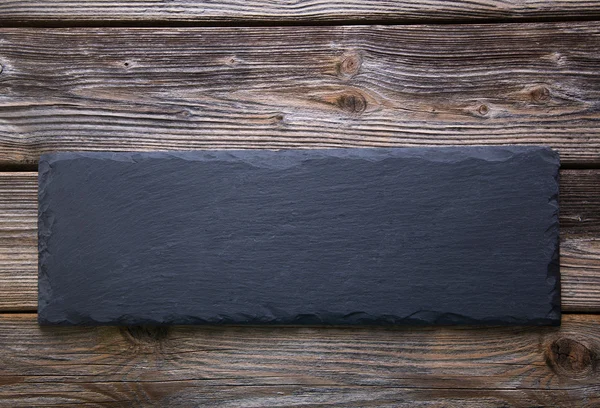 Black board of slate on old rustic wooden background. — Stock Photo, Image