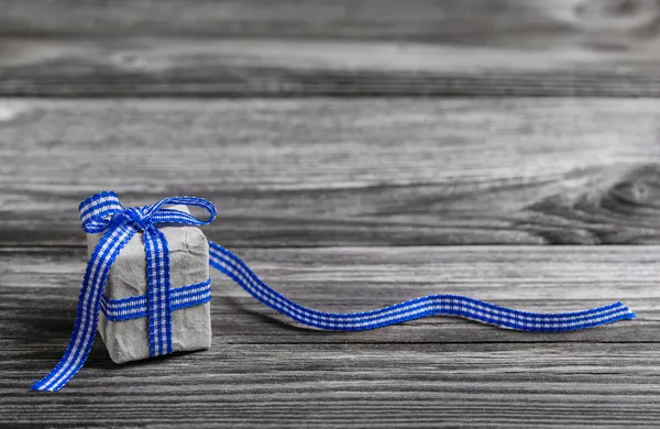 Gift box with blue checked ribbon on wooden grey background. — Stock Photo, Image