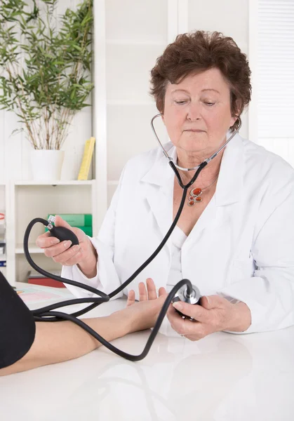 Старшая женщина-врач измеряет кровяное давление с пациентом . — стоковое фото