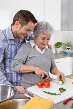 genç adam ve yaşlı kadınlarla birlikte mutfakta yemek.