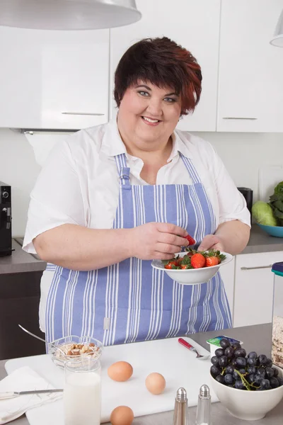 Overweight and smiling woman making breakfast. — Stock Photo, Image