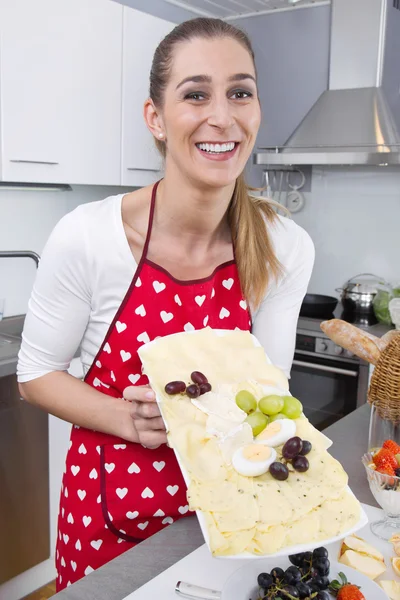 Молода усміхнена жінка представляє тарілку сиру . — стокове фото