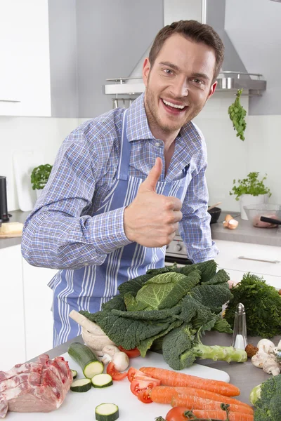 Homem na cozinha com o polegar para cima preparar o jantar . — Fotografia de Stock