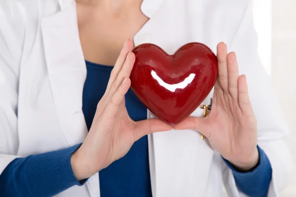 Médecin féminin tenant un cœur rouge dans ses mains - pour les concepts . — Photo