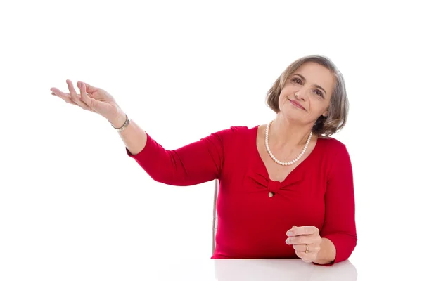 Mujer de negocios senior aislada en rojo presentando con la mano . — Foto de Stock