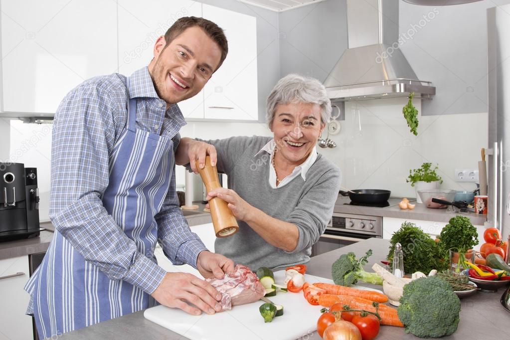 Young man and older woman cooking together in the kitchen.