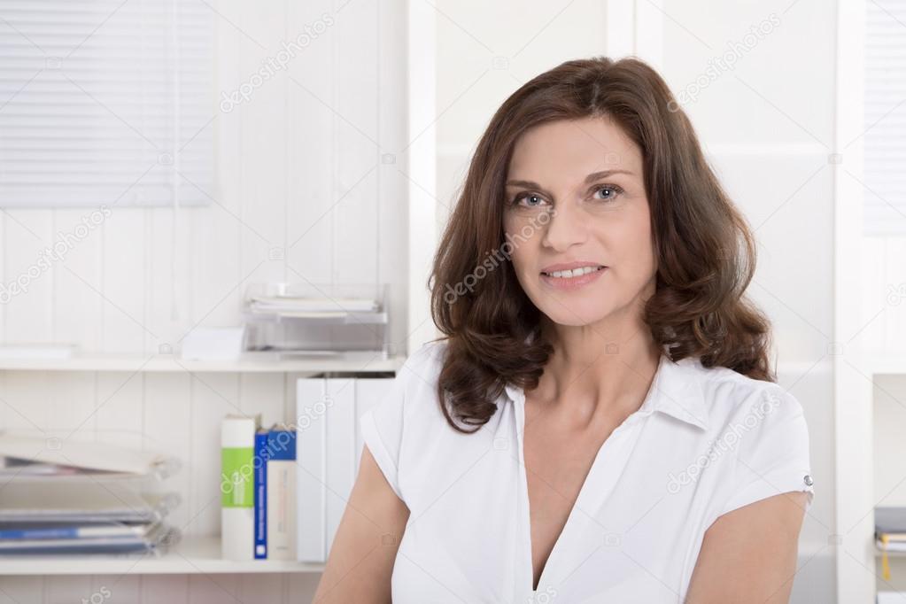 Female middle-aged doctor in portrait sitting at desk.