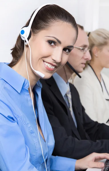 Lächelnde Frau am Telefon in einem Call Center mit blauer Bluse. — Stockfoto