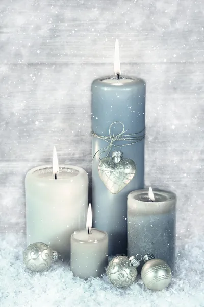 Four blue, grey and white burning christmas candles with snow in — Stock Photo, Image