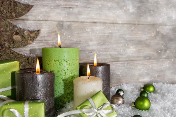 Vier brennende Adventskerzen in grün und braun auf Holzrücken — Stockfoto